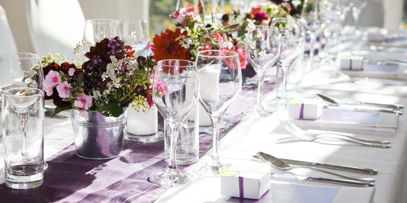 Festlich eingedeckte Hochzeitstafel mit violettem Tischläufer und bunten Blumendekorationen – Hochzeitsplanerin Köln